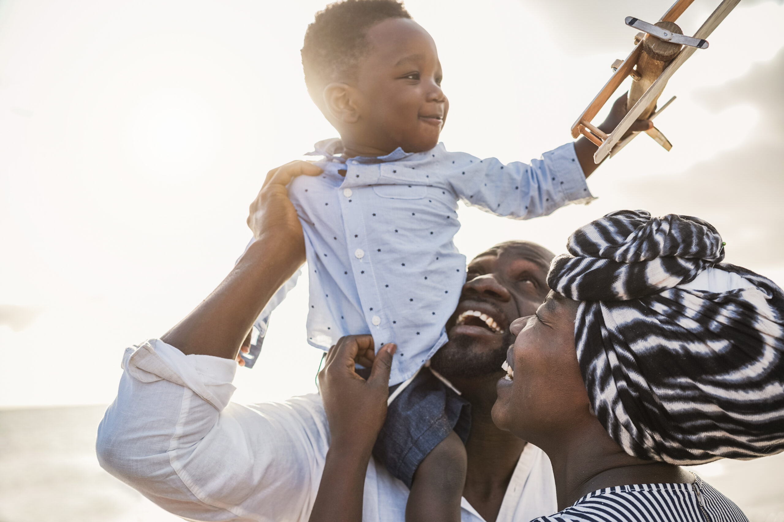 african parents and little son having fun with wood airplane on